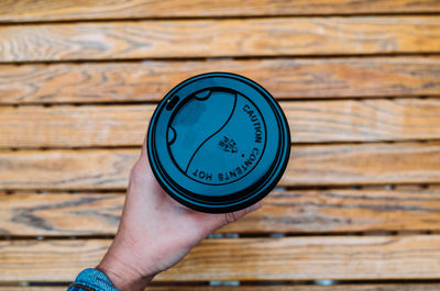 Close-up of person holding disposable cup on table 