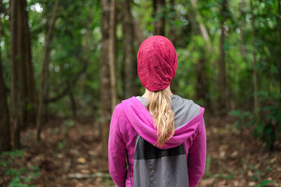 Rear view of woman standing against trees in forest