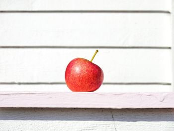 Close-up of apple on table against wall