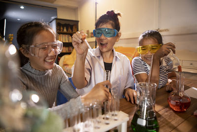 Cheerful teacher with students doing experiment in laboratory