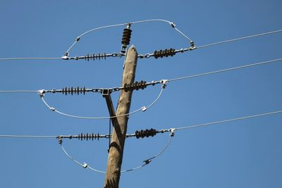 Low angle view of power lines against clear blue sky
