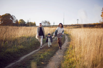 Stylish family with a boy child on a field in the dry grass in autumn