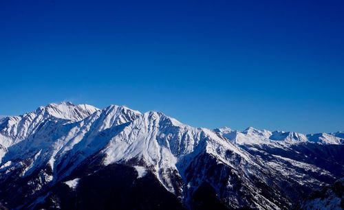 Scenic view of snowcapped mountains against clear blue sky