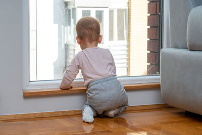 Side view of young man sitting on floor at home