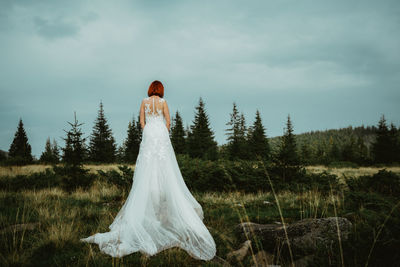 Rear view of woman standing on field against sky