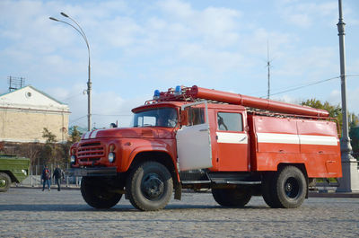 View of vehicles on road against cloudy sky