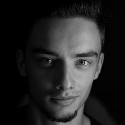 Close-up portrait of young man against black background