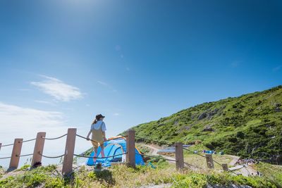 Woman standing on mountain against clear blue sky