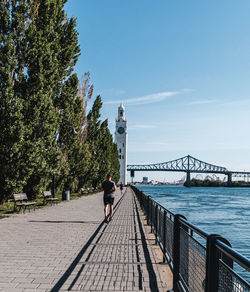 People on bridge amidst trees against sky