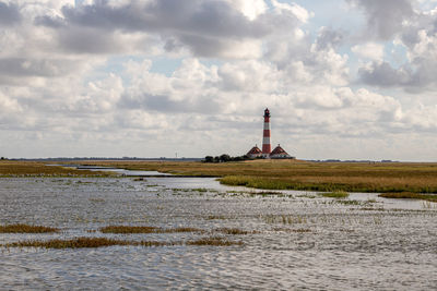 Lighthouse by sea against sky