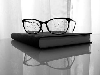 Book and wet eyeglass on table at home