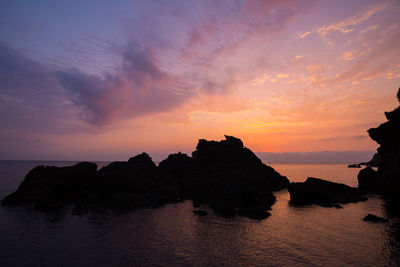 Rock formation on sea against sky during sunset