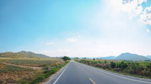 Empty road along landscape against sky