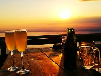 Beer on table against sky during sunset