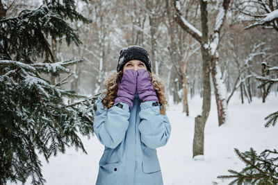 Hello winter, happy wintertime. happy young curly woman with hands raised up celebrating winter