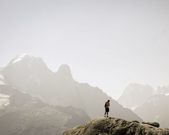 Hiker standing on rock against mountains