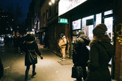 Woman walking in illuminated city at night
