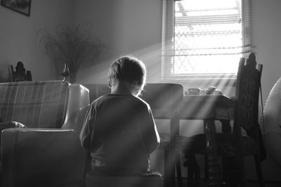 Rear view of boy sitting on seat at home