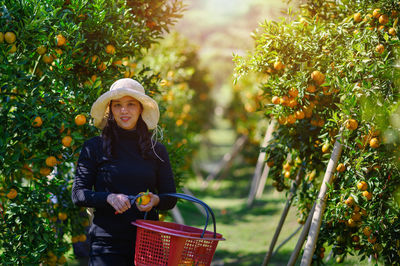 Portrait of smiling young woman against trees