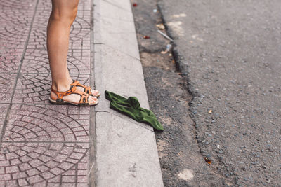 Low section of woman standing by socks on footpath
