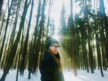 Portrait of woman against forest during winter