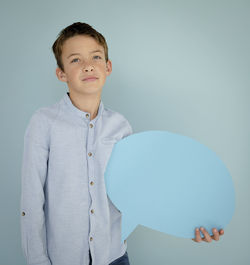 Portrait of smiling young woman with balloons against blue background