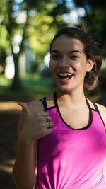 Portrait of smiling teenage girl gesturing while standing at park