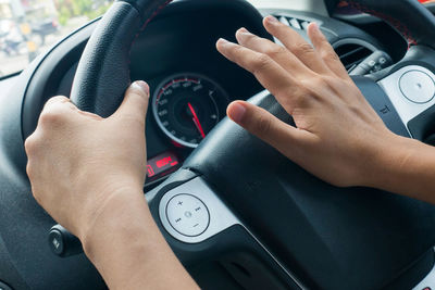 Cropped hands of woman driving car