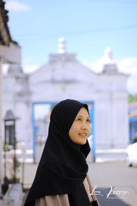 Young woman standing against building