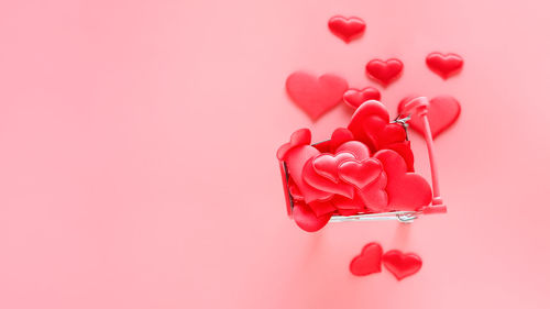 High angle view of red heart shape over pink background