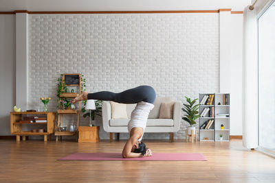 Side view of woman sitting on hardwood floor at home