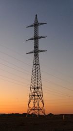 Low angle view of silhouette electricity pylon against clear sky during sunset