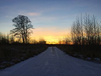 Snow covered landscape against sky during sunset