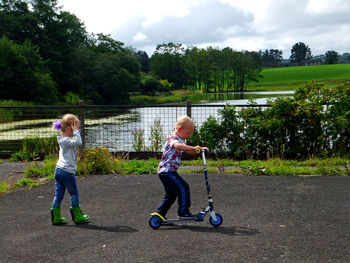 Siblings playing with push scooter outdoors