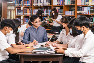 Professor teaching students wearing masks at library