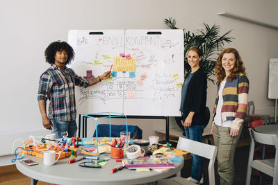 Portrait of confident technician team standing strategy on whiteboard at creative office