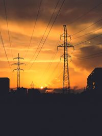 Low angle view of silhouette electricity pylon against sky during sunset