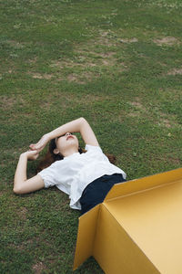 Woman lying on grass in cardboard box