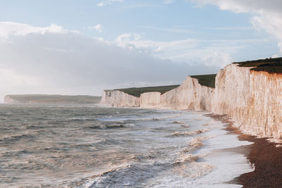 Waves hitting the beach by seven sisters chalk cliffs in east sussex, uk.