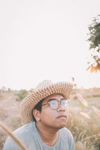 Portrait of young man looking away against sky