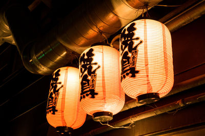 Low angle view of illuminated lighting equipment hanging on ceiling