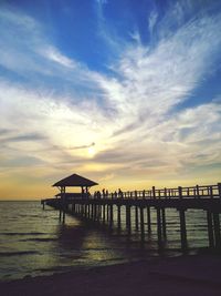 Pier over sea against sky during sunset