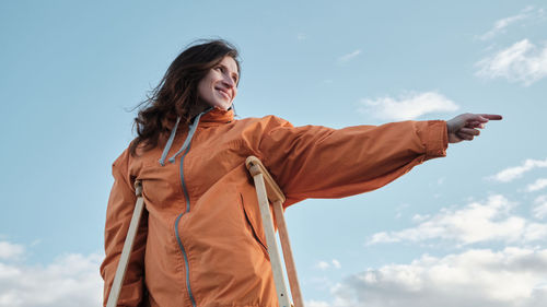 A woman on crutches points with her hand