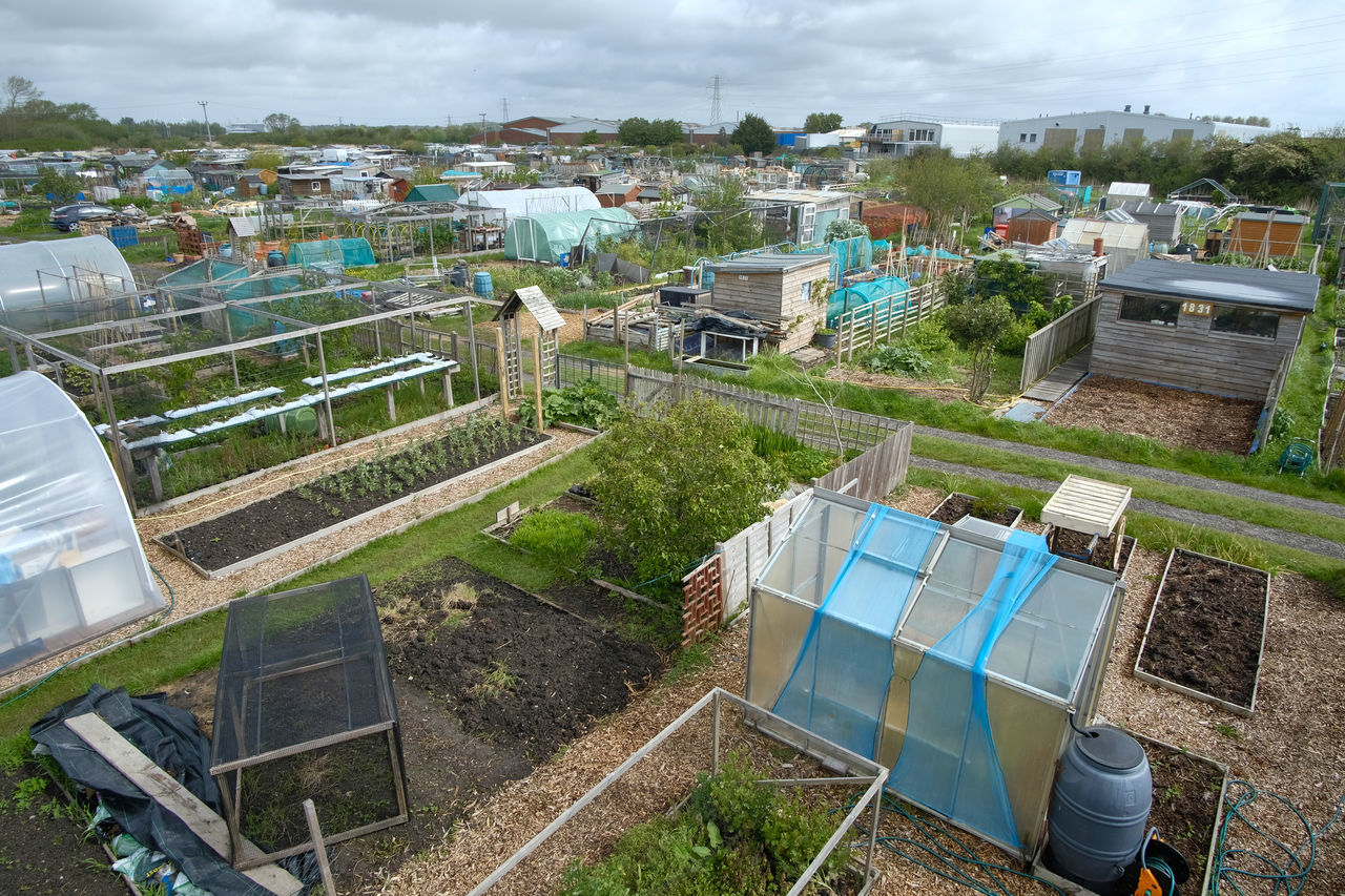 HIGH ANGLE VIEW OF BUILDINGS ON FIELD AGAINST SKY