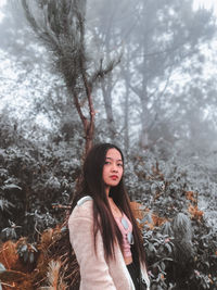 Portrait of young woman standing in forest