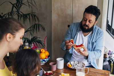 Man eating food while sitting with family at table