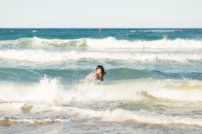 Man surfing in sea against sky