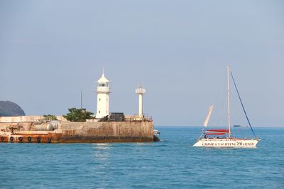 Lighthouse by sea against clear sky