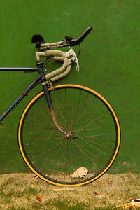 Road bycicle with yellow tires resting on a green wall