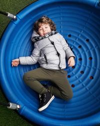 Portrait of cute boy lying on outdoor play equipment